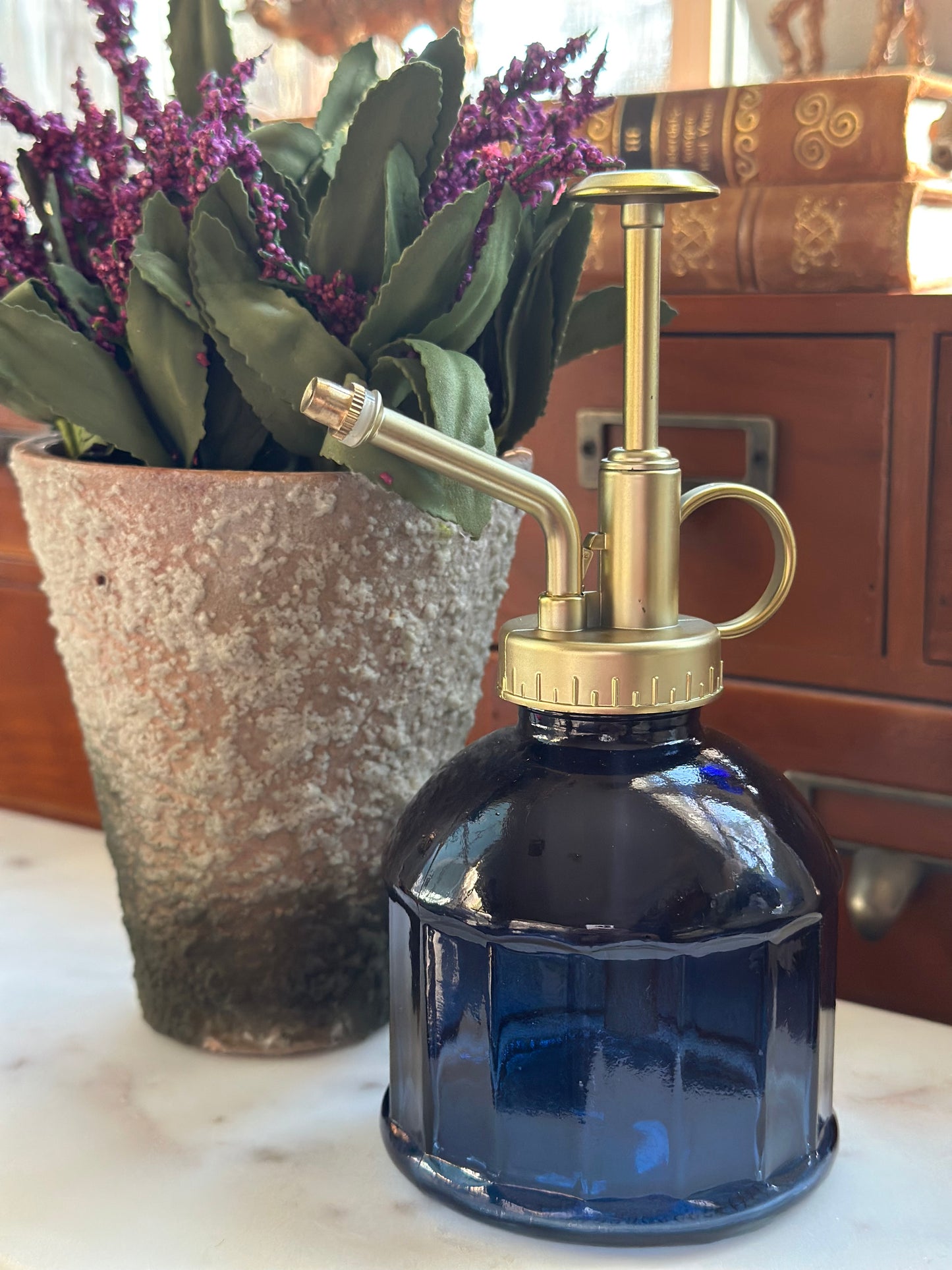 Elegant blue glass plant mister with a brass nozzle, perfect for gentle watering. Refillable and efficient misting for houseplants and succulents.