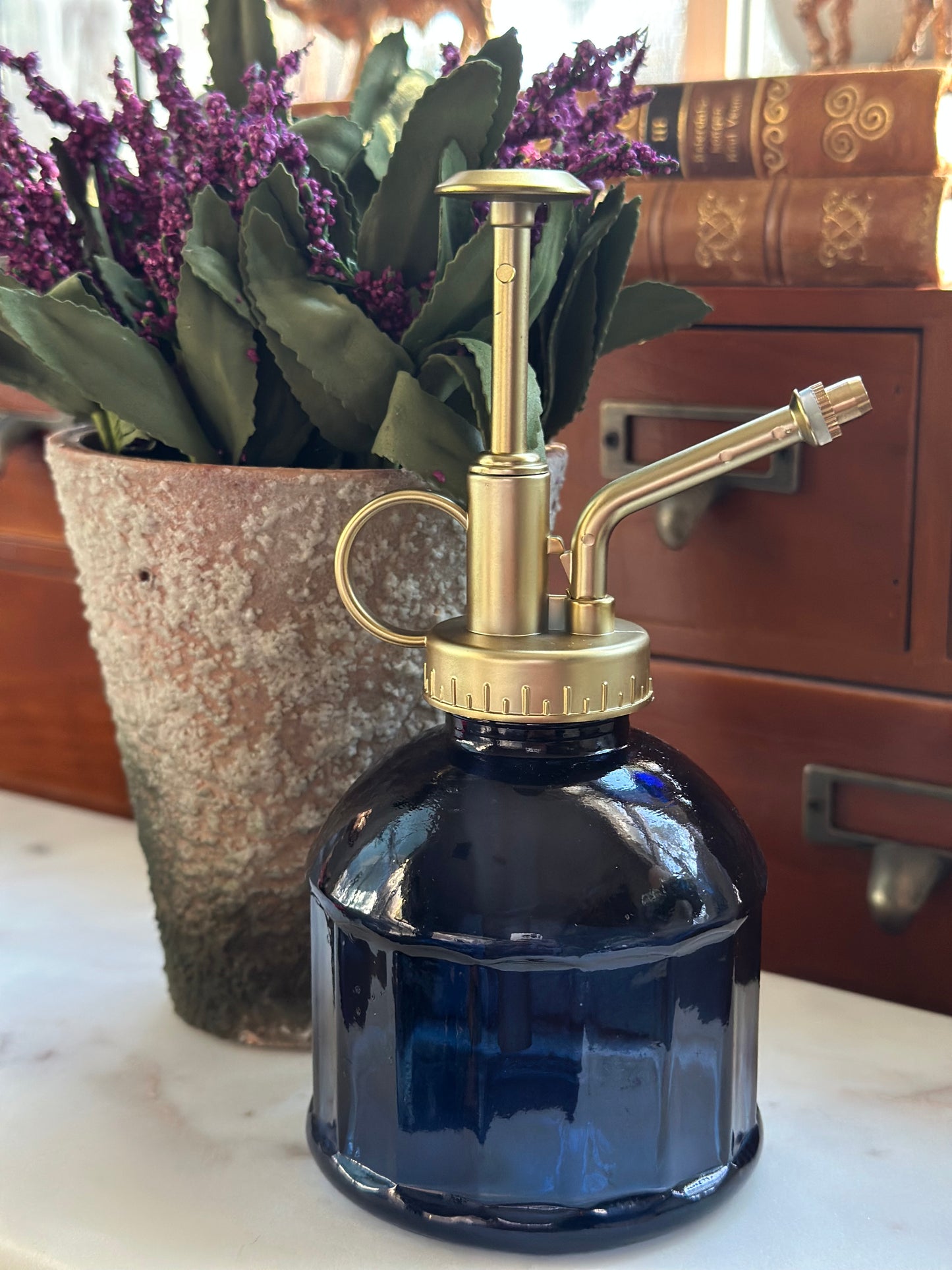 Glass mister in blue with a brass pump, ideal for watering plants with a fine mist. Stylish and water-saving design for indoor gardening.