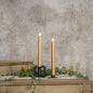 Set of two 9.5-inch 3D Flame Gold Taper Candles with a realistic flickering glow, displayed on a rustic wooden surface with greenery accents.
