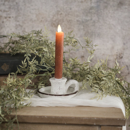 Rustic brown and white taper candle holder with handle, crafted from terracotta. Features a speckled white glaze and earthy brown rim for vintage charm.