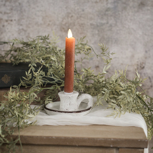 Rustic brown and white taper candle holder with handle, crafted from terracotta. Features a speckled white glaze and earthy brown rim for vintage charm.