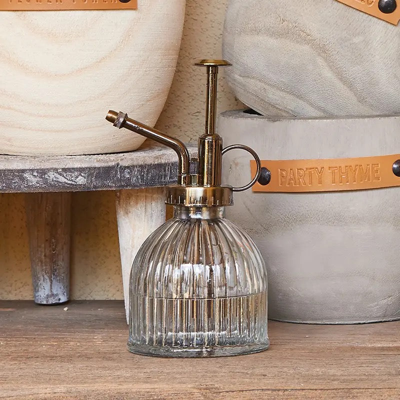 Elegant Glass Mister - Clear with vintage brass pump, displayed in a rustic setting. Ideal for gentle plant watering and home decor.