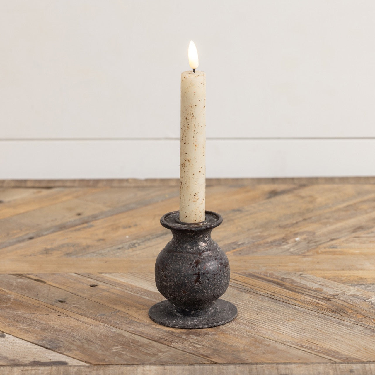 3.5-inch Jasper taper candle holder with a rustic metal finish, holding a lit candle. A perfect accent for home décor with vintage charm.