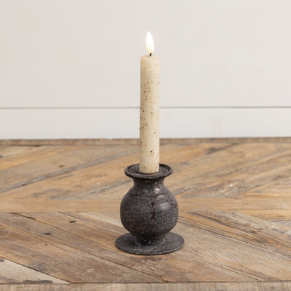 3.5-inch Jasper taper candle holder with a rustic metal finish, holding a lit candle. A perfect accent for home décor with vintage charm.