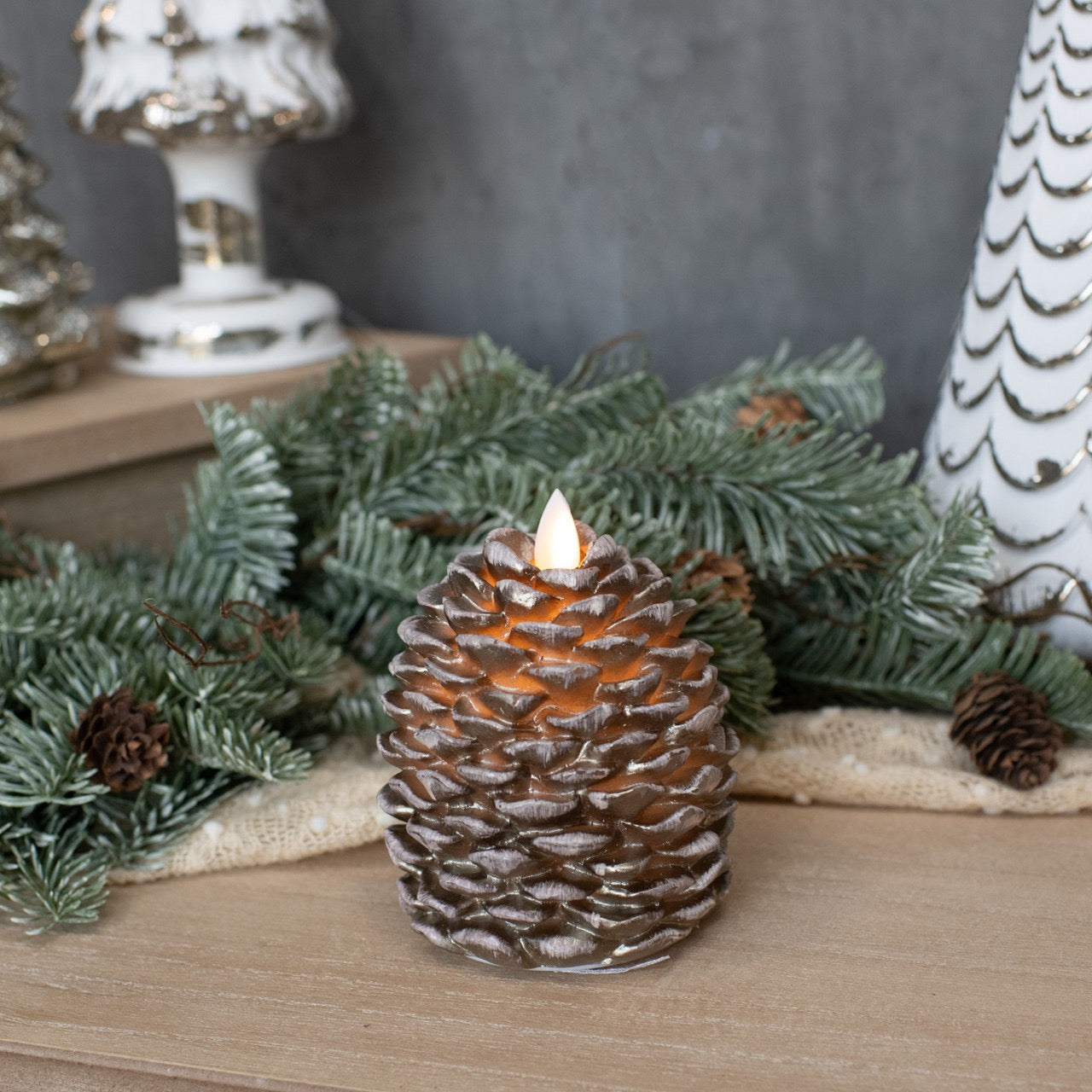 Decorative Moving Flame Pinecone Candle - 4.25" placed among holiday greenery, creating a cozy and festive ambiance.