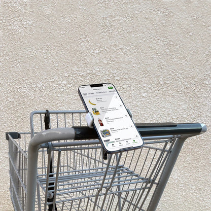 TECH CANDY ROLL WITH IT phone holder attached to a shopping cart handle, securely holding a smartphone for easy access while shopping.