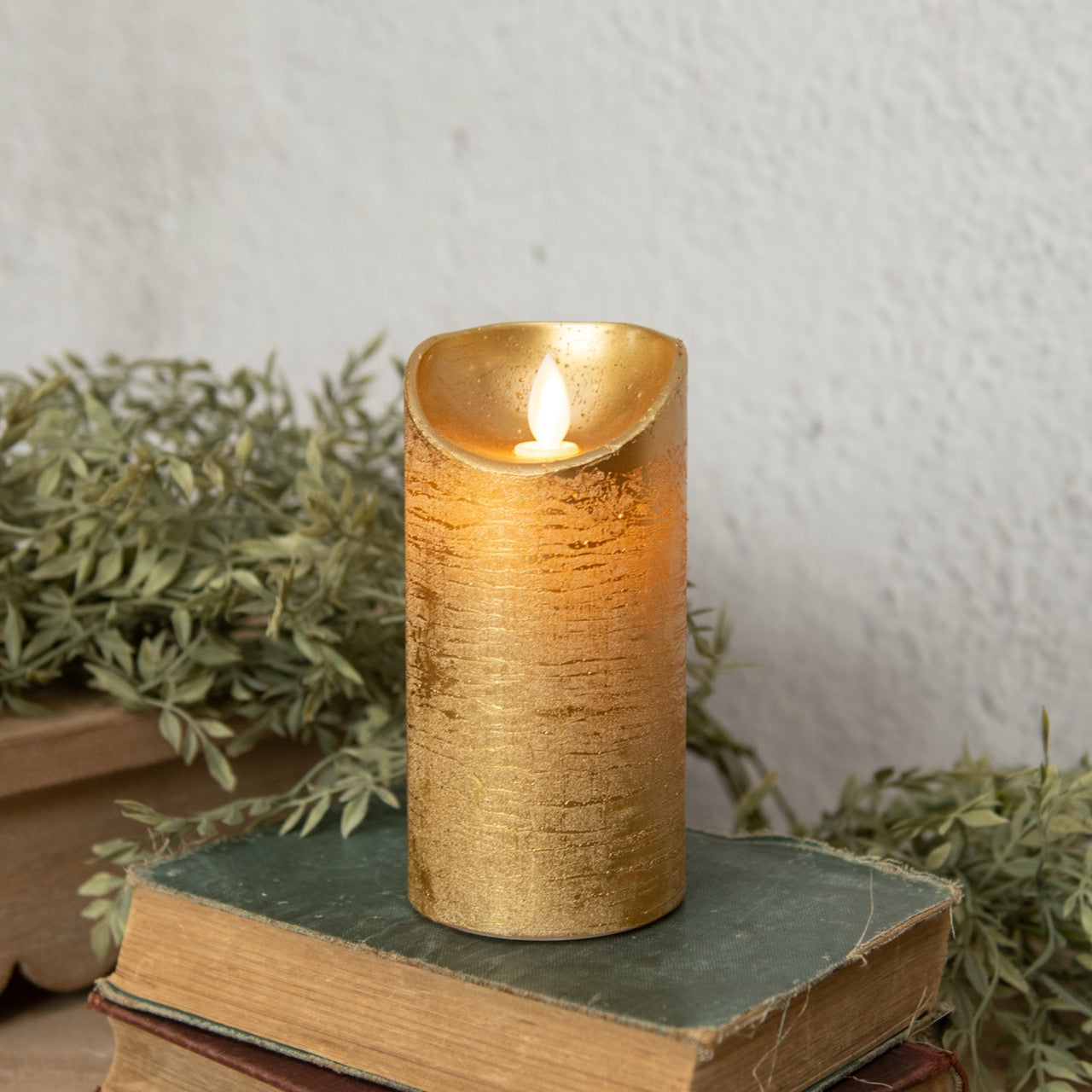 6-inch gold pillar candle with a moving flame, placed on vintage books. Ideal for elegant home decor and ambient lighting.