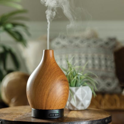 Woodgrain Vase Ultra Sonic Diffuser releasing mist in a cozy home setting. Enhances ambiance with essential oils and stylish decor.