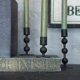 Sculpted taper candlestick in black metal, 4.5-inch size, elegantly displayed with green candles. Perfect for home decor and ambiance enhancement.