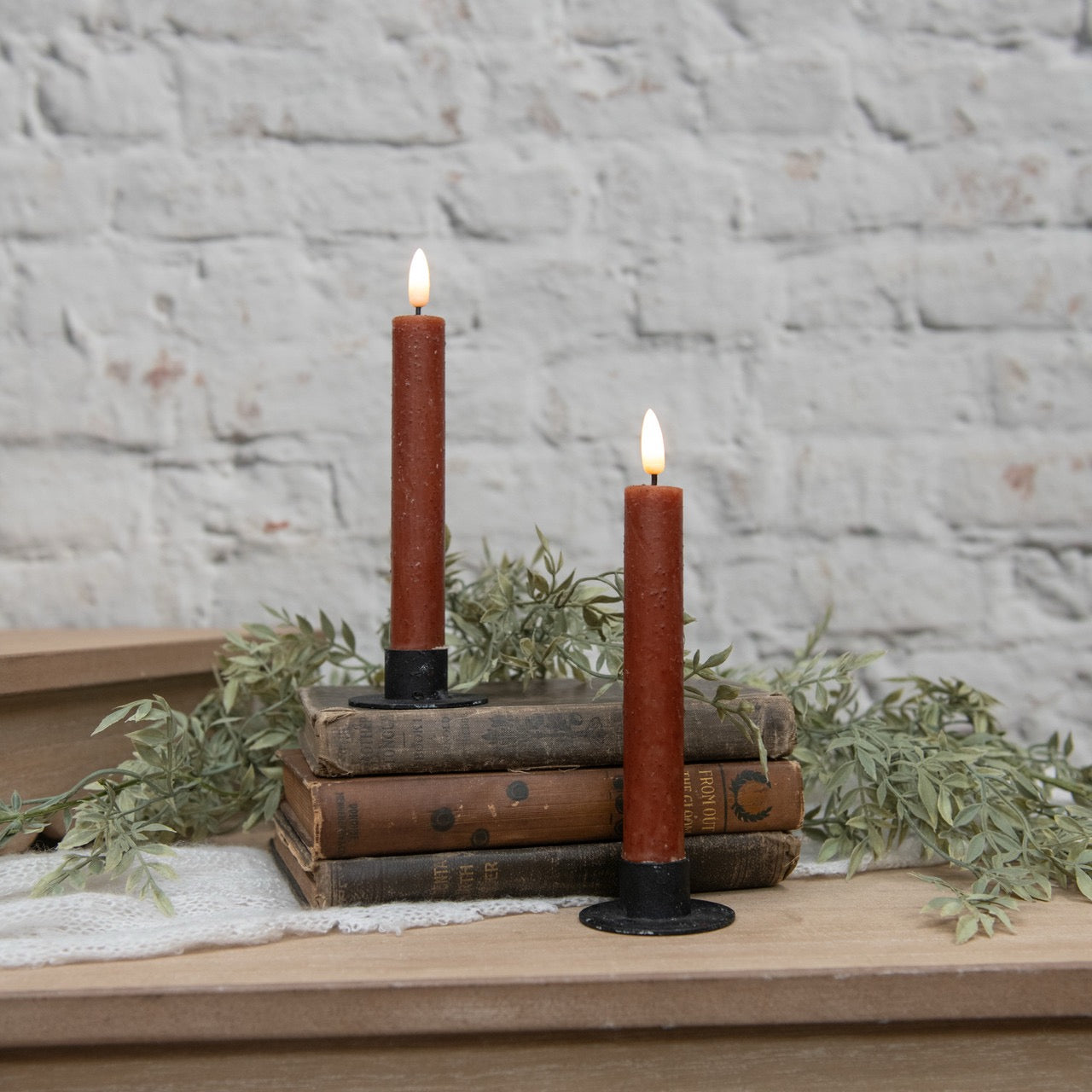 Set of 2 3D Flame Bronze Taper Candles, 7.25 inches tall, displayed on vintage books with greenery. Realistic flameless design for cozy ambiance.