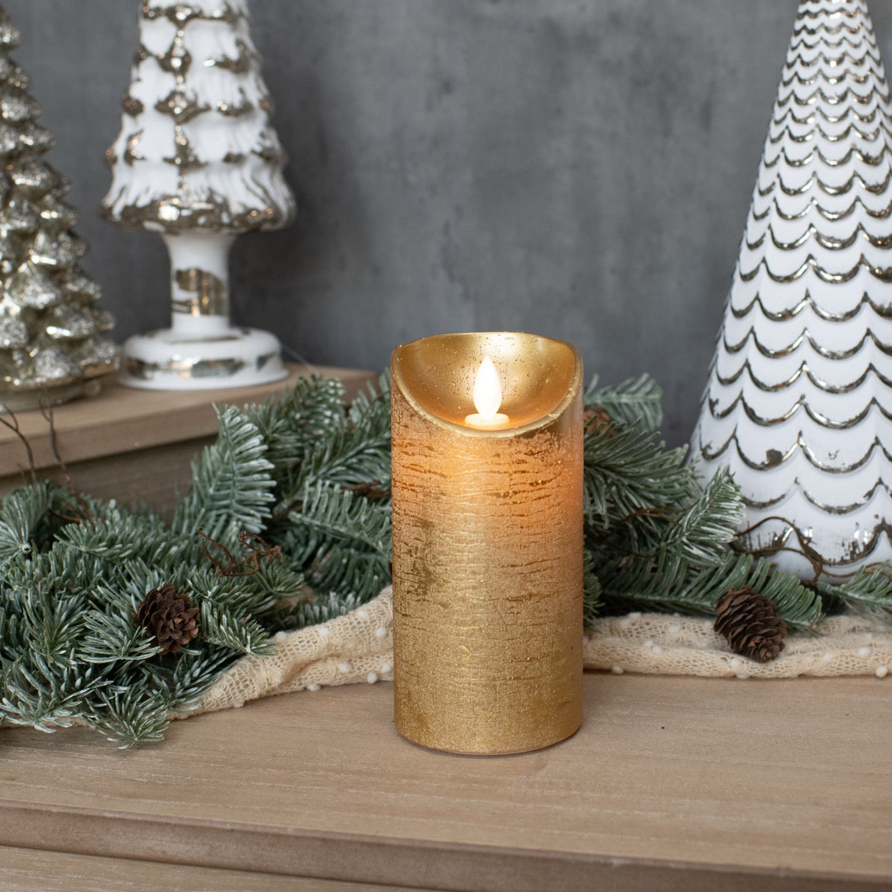 Gold pillar candle with a moving flame, 6-inch size, styled with festive decor and greenery. Perfect for holiday and home ambiance.