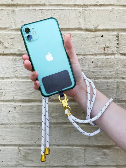 Hand holding a smartphone attached to the TECH CANDY HOOKUP white lanyard with gold accents. Secure and stylish phone strap for easy carrying.