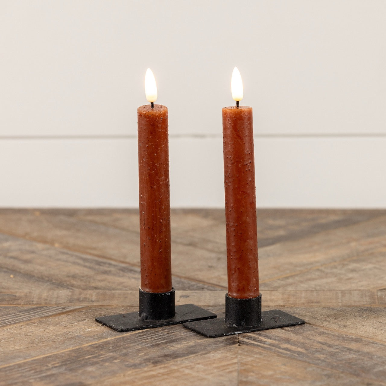 Pair of 3D Flame Bronze Taper Candles, 7.25 inches, with a flickering flameless glow on black metal holders. Elegant home decor accent.