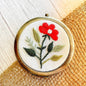 Handcrafted floral embroidered compact mirror from Quince Fables, featuring a red flower on a cream fabric background.