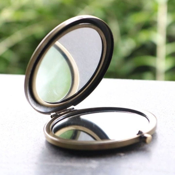 Open floral embroidered compact mirror from Quince Fables, showcasing dual mirrors with a vintage brass finish.