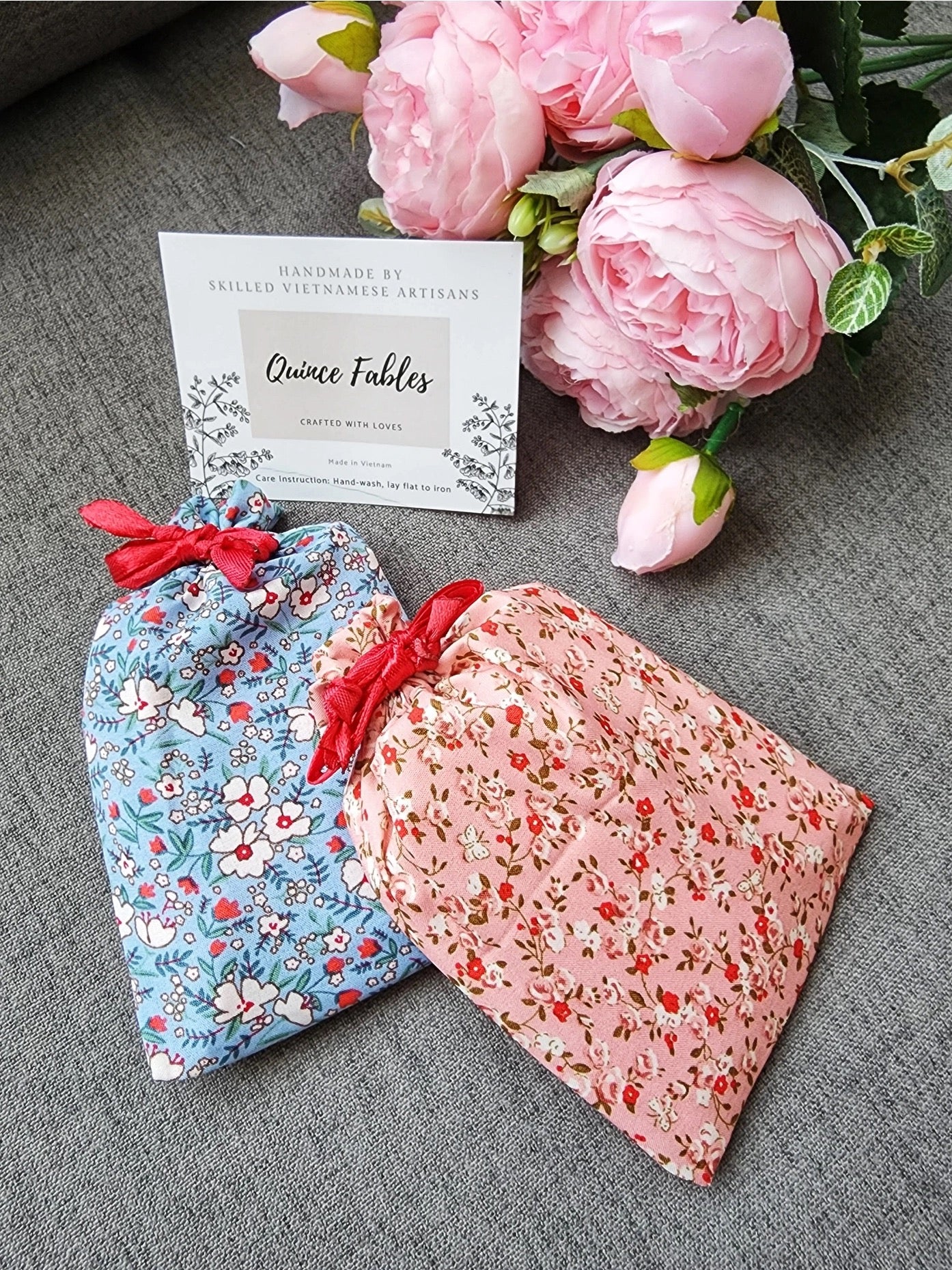 Floral fabric pouches from Quince Fables, designed for storing handcrafted embroidered compact mirrors, with a brand card in the background.