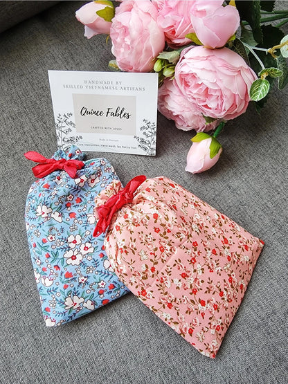 Floral fabric pouches from Quince Fables, designed for storing handcrafted embroidered compact mirrors, with a brand card in the background.