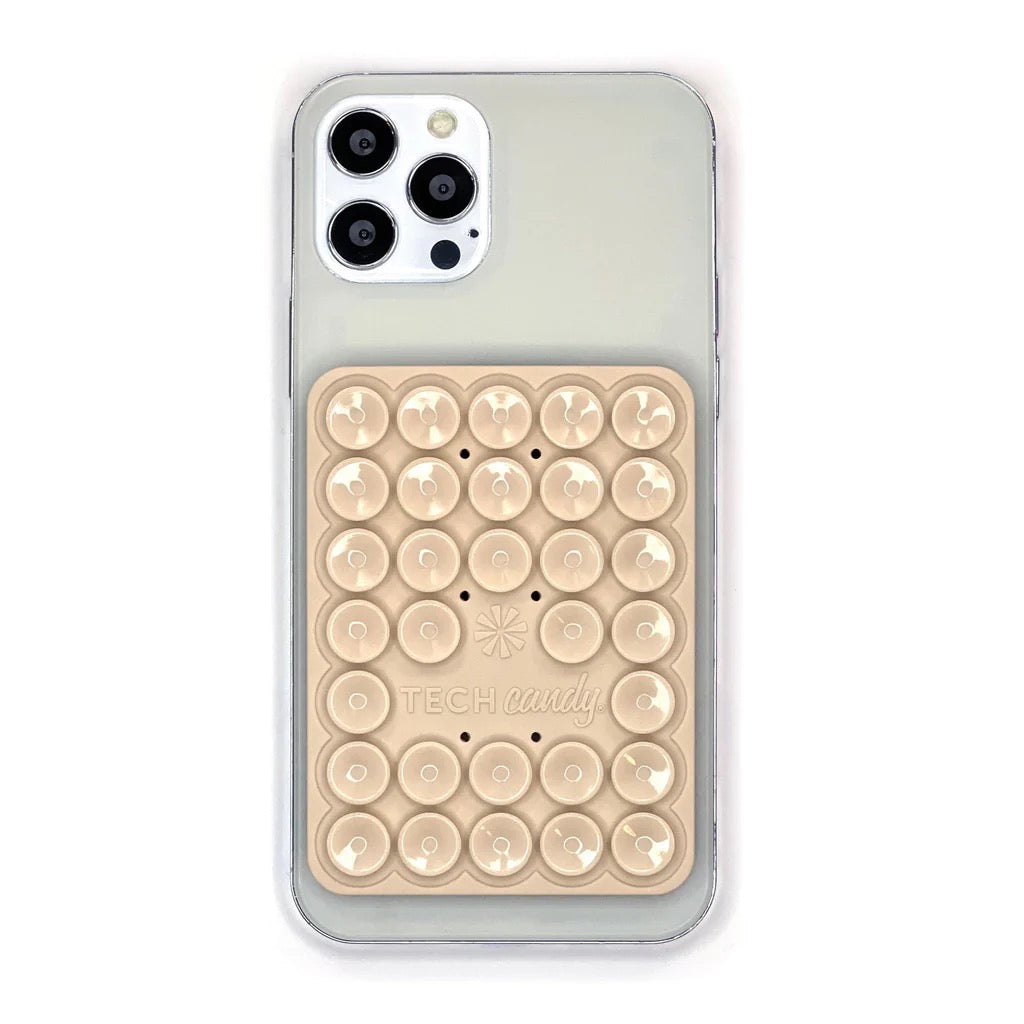 TECH CANDY STICK 'EM UP 2-SIDED PHONE SUCTION PAD in beige attached to the back of a smartphone. Ideal for hands-free use and secure grip.